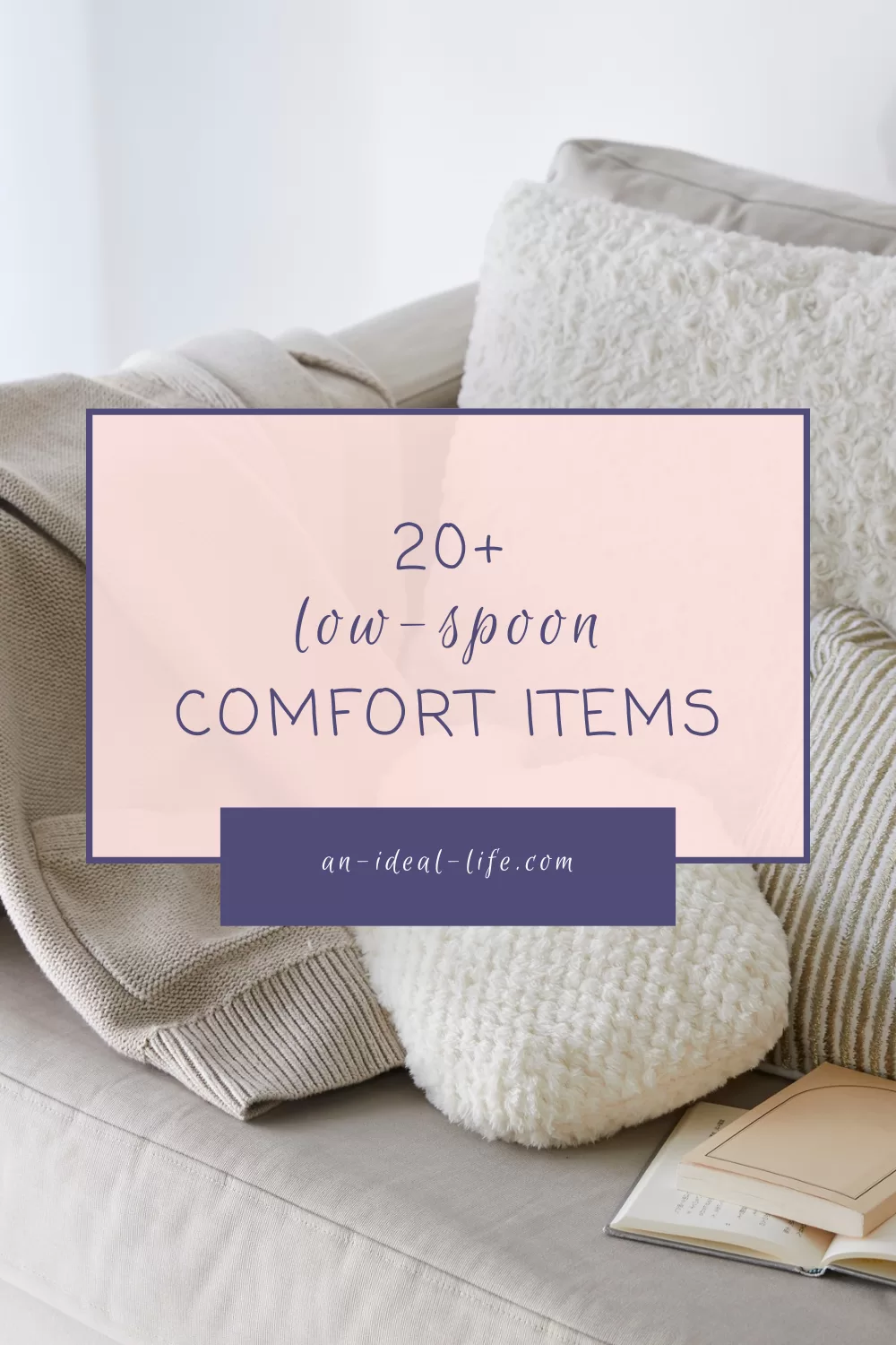 A soft, neutral-toned living room scene featuring cozy elements like a beige knit blanket, a white fluffy pillow, a striped cushion, and an open book on a light grey sofa. Overlay text reads: "20+ low-spoon COMFORT ITEMS" with the website "an-ideal-life.com" displayed in a purple box. The overall tone is calm and comforting, promoting a blog post about accessible comfort items for those with limited energy.